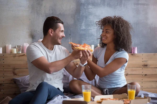 couple feeding each other with pizza