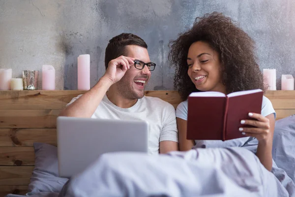 Coppia utilizzando computer portatile e libro di lettura — Foto Stock