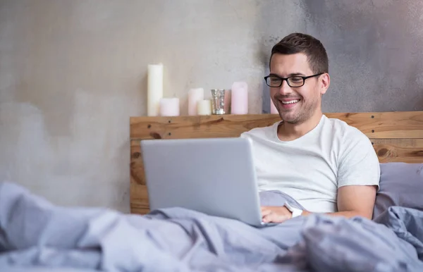 Człowiek za pomocą laptopa w łóżku — Zdjęcie stockowe