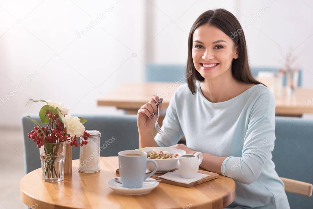 Charming young woman eating healthy food in a cafe.