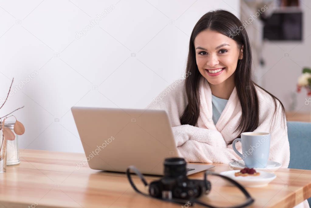 Joyful beautiful woman using laptop in a cafe.