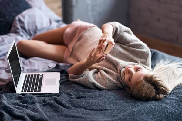 Mulher relaxada usando smartphone na cama — Fotografia de Stock