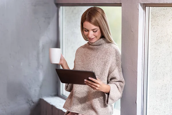 Pretty woman drinking coffee using tablet