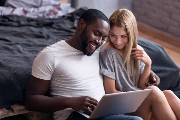 Glada paret sitter i sovrummet med laptop — Stockfoto