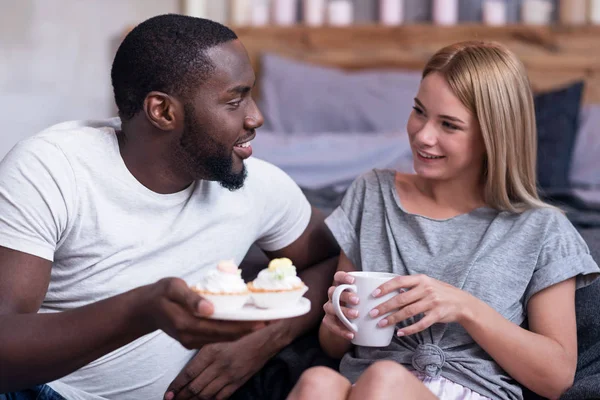 Glada par njuter av muffins tillsammans i sängen — Stockfoto