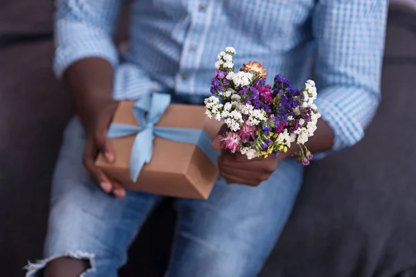 Gros plan sur les cadeaux et les fleurs détenus par l'homme africain — Photo