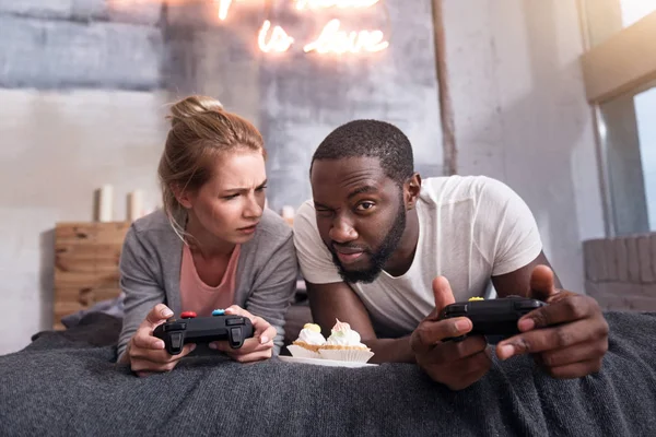 Pareja muy alegre comiendo cupcakes y jugando juegos — Foto de Stock