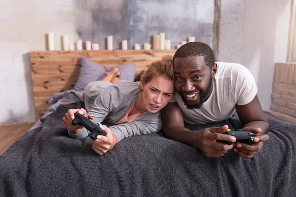 Pareja muy alegre disfrutando de los videojuegos en la cama — Foto de Stock