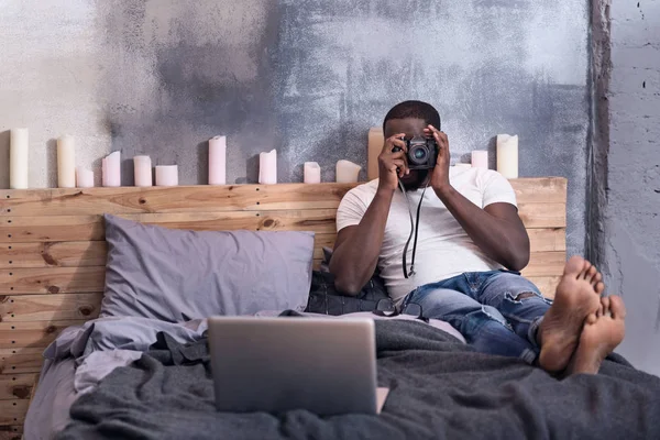 Uomo africano che tiene una macchina fotografica in camera da letto — Foto Stock