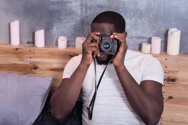 Hombre concentrado sosteniendo una cámara fotográfica en la cama —  Fotos de Stock