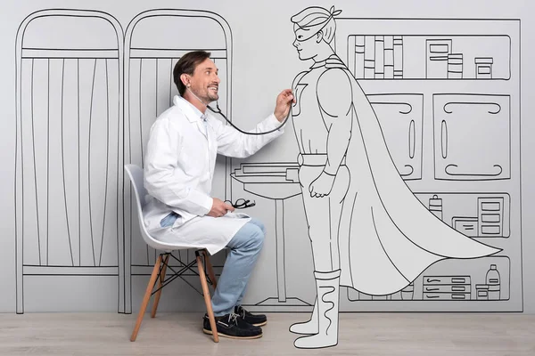 Happy smiling doctor examining superman.