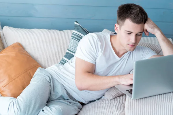 Koncentruje się młody człowiek korzysta z laptopa. — Zdjęcie stockowe