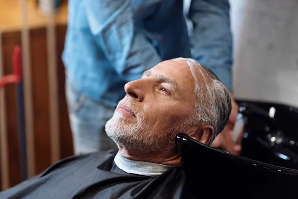 Old man during washing his hair in barber shop — Stock Photo, Image