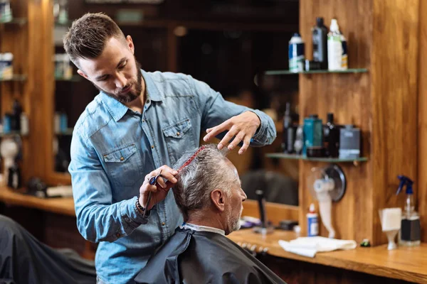 Viejo hombre teniendo corte de pelo por joven especialista —  Fotos de Stock