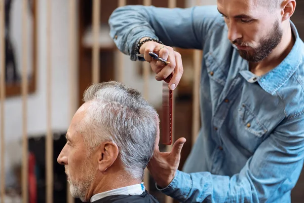 Peluquero haciendo corte de pelo a hombre mayor — Foto de Stock