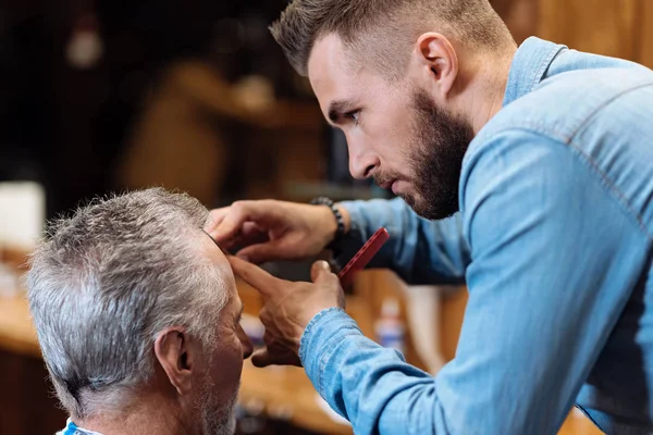Hair dresser cutting bang of senior man — Stock Photo, Image