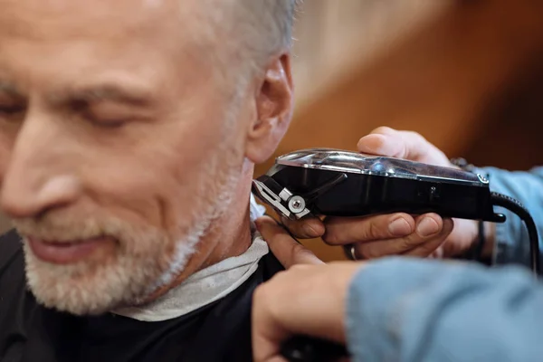 Senior man being trimmed at barbershop