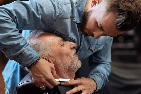 Cabeleireiro atraente é barbear barba masculina com a faca — Fotografia de Stock