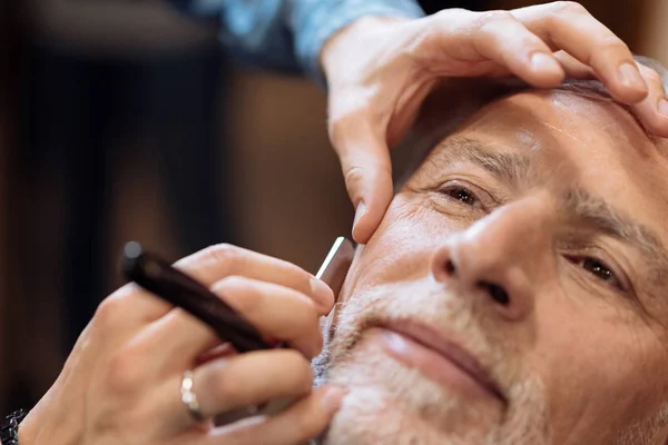 Крупным планом милого пожилого человека, которого брили в парикмахерской — стоковое фото