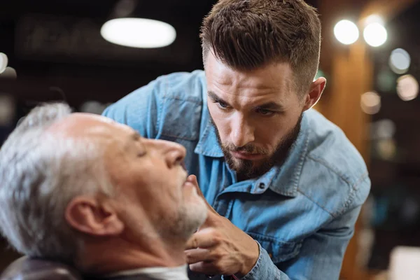 Barber cutting beard of senior client with scissors — Stock Photo, Image