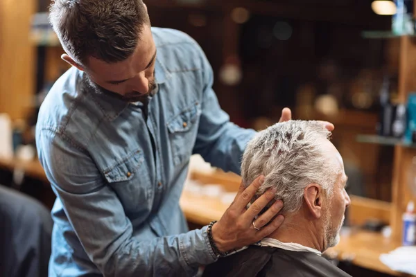高齢者のクライアントの髪をスタイリング床屋の背面図 — ストック写真