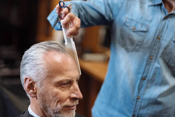 Close up of barber combing senior client hair — Stock Photo, Image