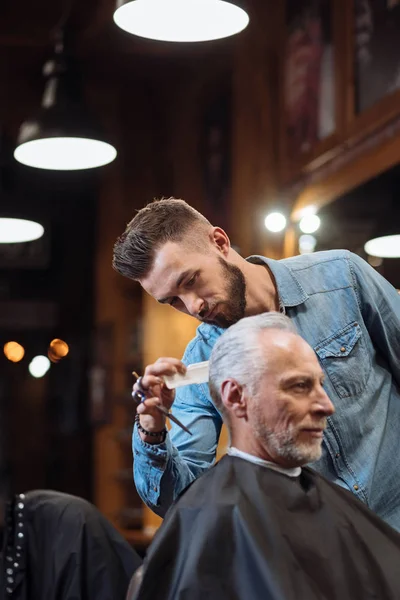 Guapo peluquero haciendo corte de pelo a hombre mayor —  Fotos de Stock