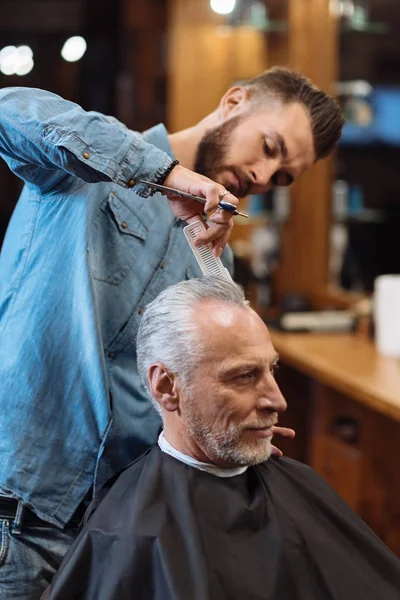 Bello parrucchiere fare taglio di capelli a uomo anziano — Foto Stock