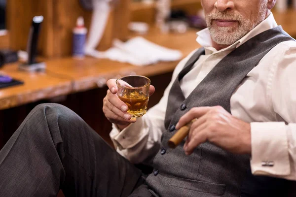 Крупный план пожилого человека со стаканом виски и сигарой — стоковое фото