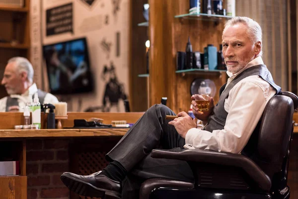 Elegante senior man met whisky glas en sigaar op barbershop — Stockfoto