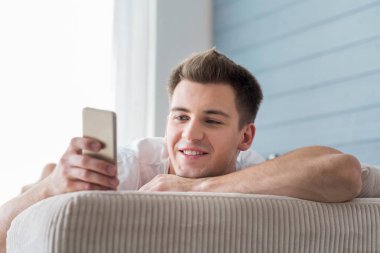 Cep telefonu kullanarak gülümseyen çekici adam.