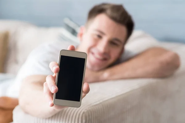 Trevlig ung man visar mobiltelefon. — Stockfoto