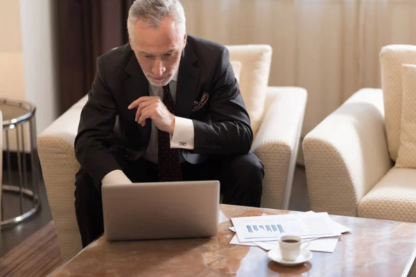 Hombre de negocios concentrado trabajando con el portátil en el hotel — Foto de Stock