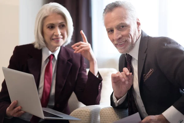 Vrolijke zakenvrouw en haar collega werken met de laptop — Stockfoto