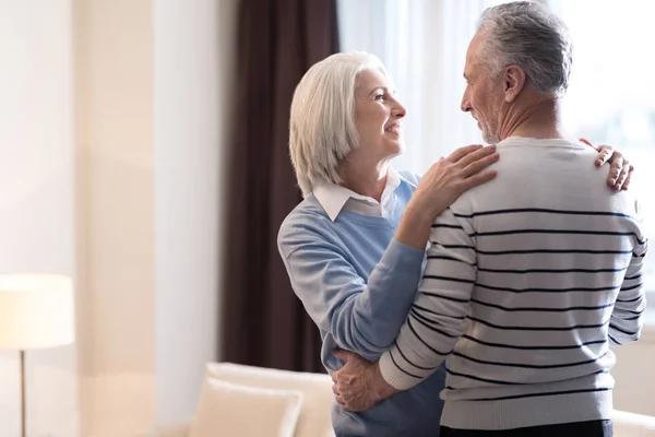 Весела старенька пара обіймає один одного вдома — стокове фото