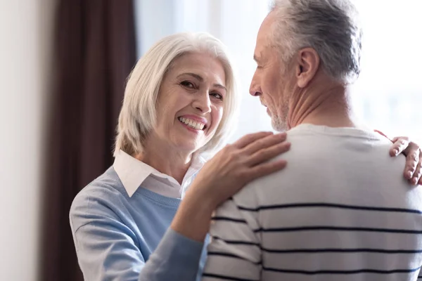 Delighted aged couple hugging each other at home — Stock Photo, Image