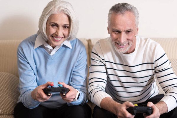 Delighted aged couple playing with game console at home