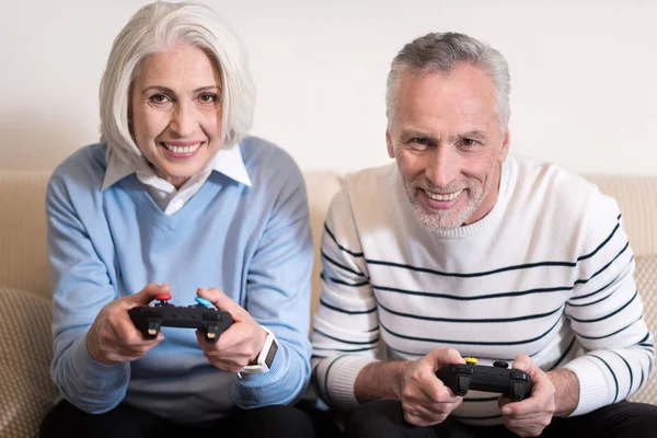 Pareja anciana involucrada jugando con la consola de juegos en casa — Foto de Stock