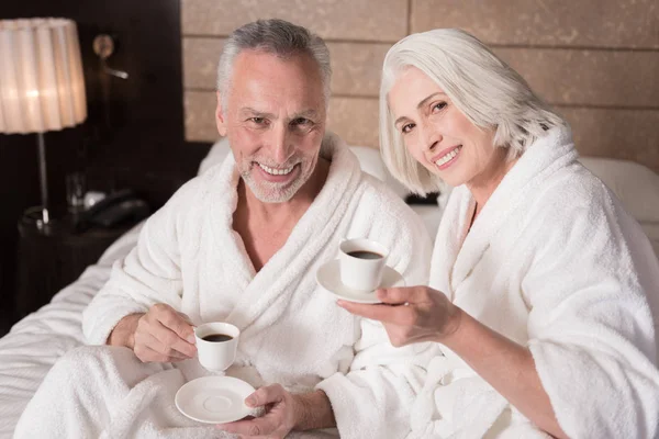 Feliz pareja de ancianos agradable beber café en la cama — Foto de Stock