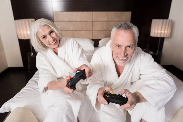 Divertida pareja de ancianos jugando juegos en la cama — Foto de Stock