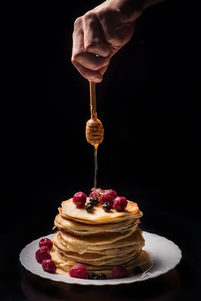 Nahaufnahme von Menschenhänden, die Pfannkuchen Honig hinzufügen — Stockfoto