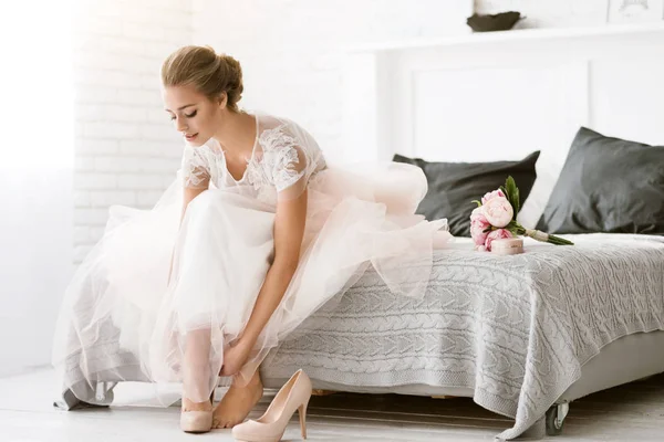 Beautiful bride sitting in the white colored room — Stock Photo, Image