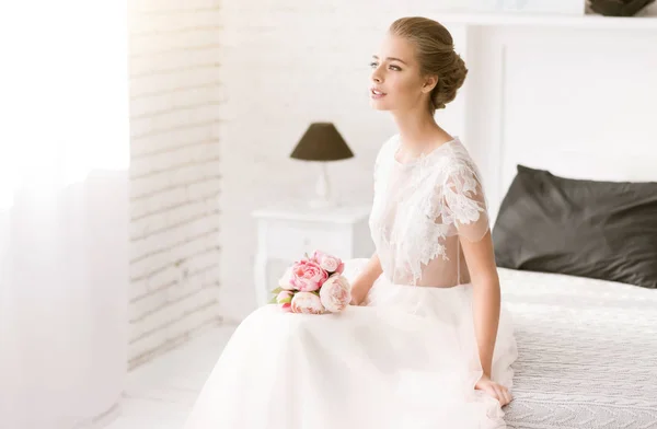 Nachdenkliche junge Braut sitzt auf dem Bett — Stockfoto