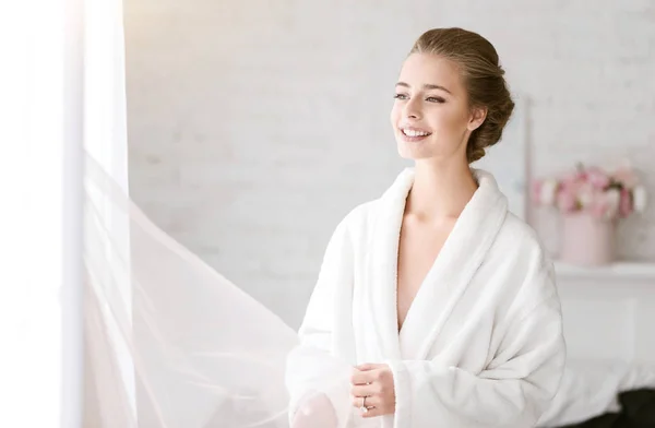 Sonriente novia de pie en la habitación de color blanco — Foto de Stock