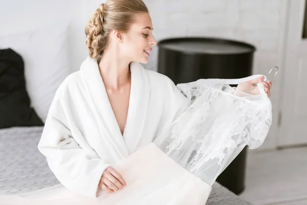 Bonito jovem noiva segurando seu vestido de noiva — Fotografia de Stock