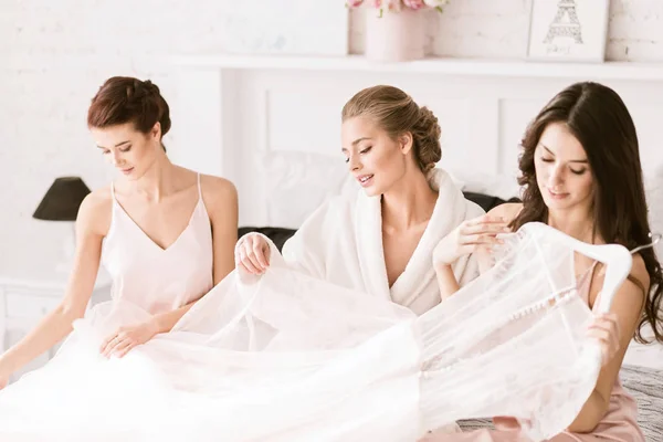 Carino giovane sposa guardando il suo abito da sposa — Foto Stock