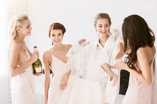 Cheerful bridesmaids helping the bride to get ready for wedding