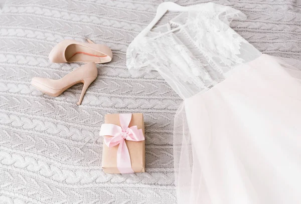 白色的婚纱礼服和鞋子躺在床上 — 图库照片