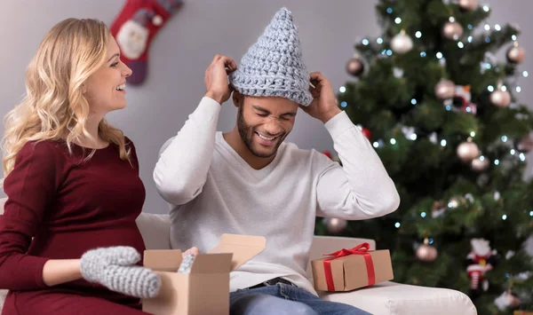 Positive young man putting a knitted hat on his head — Stock Photo, Image