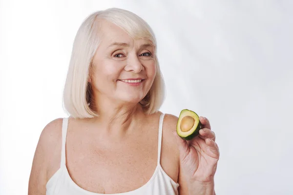 Mujer sosteniendo una mitad de aguacate — Foto de Stock